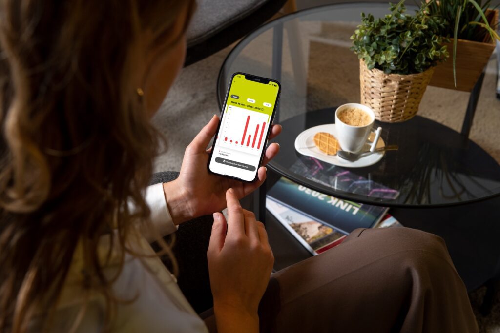 Gebruiker controleert energieverbruik thuis met Ilusmart app op smartphone.
